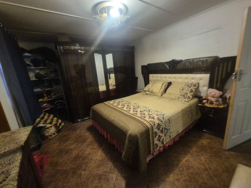 A bedroom featuring tiled flooring, a ceiling rose, and a built-in wardrobe.