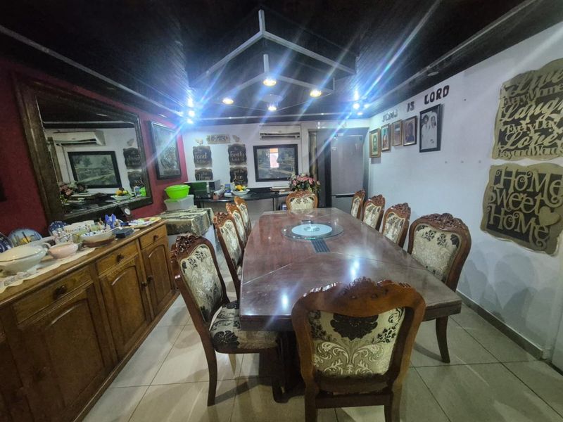 A dining room featuring an exposed timber ceiling, recessed lighting, and tiled flooring, providing a functional space for family meals.