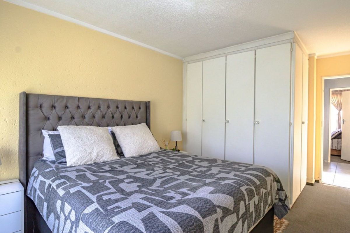 A bedroom featuring built-in cupboards and carpeted flooring, providing functional storage space within the apartment.