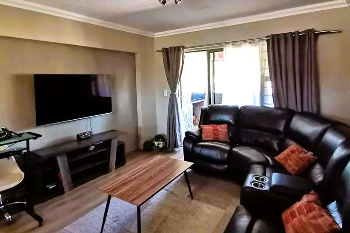 A comfortable living room featuring laminate flooring, cove ceiling molding, and a sliding glass door providing access to the outdoor area.