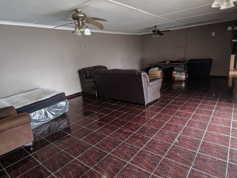 Spacious living area featuring dark tiled flooring and dual ceiling fans, offering a blank canvas for renovation and interior design updates.