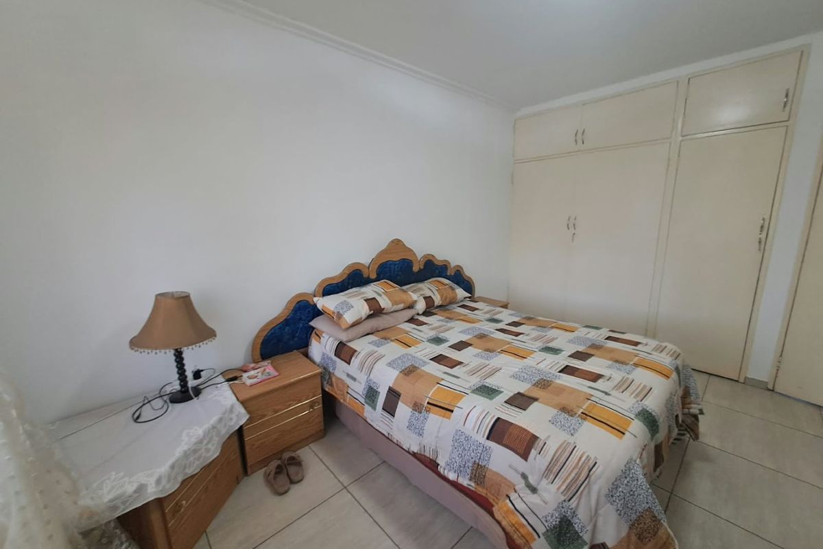 A functional bedroom featuring tiled flooring and built-in cupboards, offering a neutral base for potential interior updates.