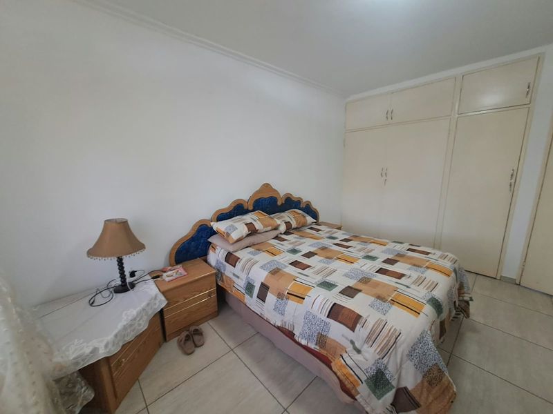 A functional bedroom featuring tiled flooring and built-in cupboards, offering a neutral base for potential interior updates.