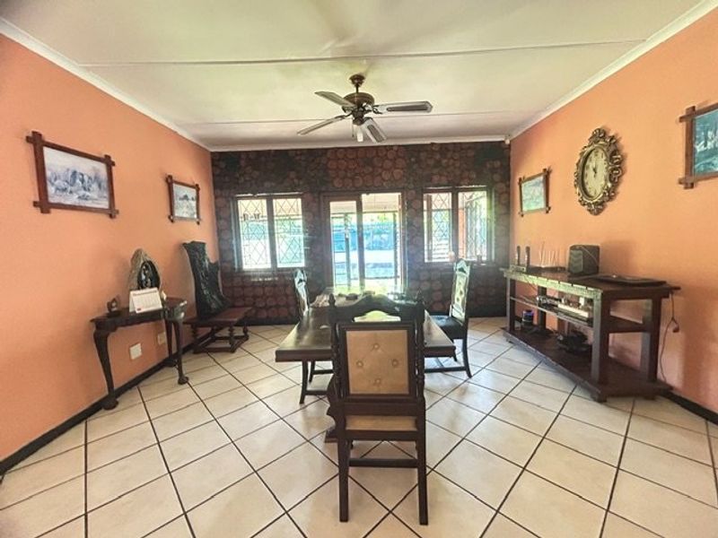 Spacious dining room featuring tiled flooring, a ceiling fan, and sliding glass doors leading to the exterior.
