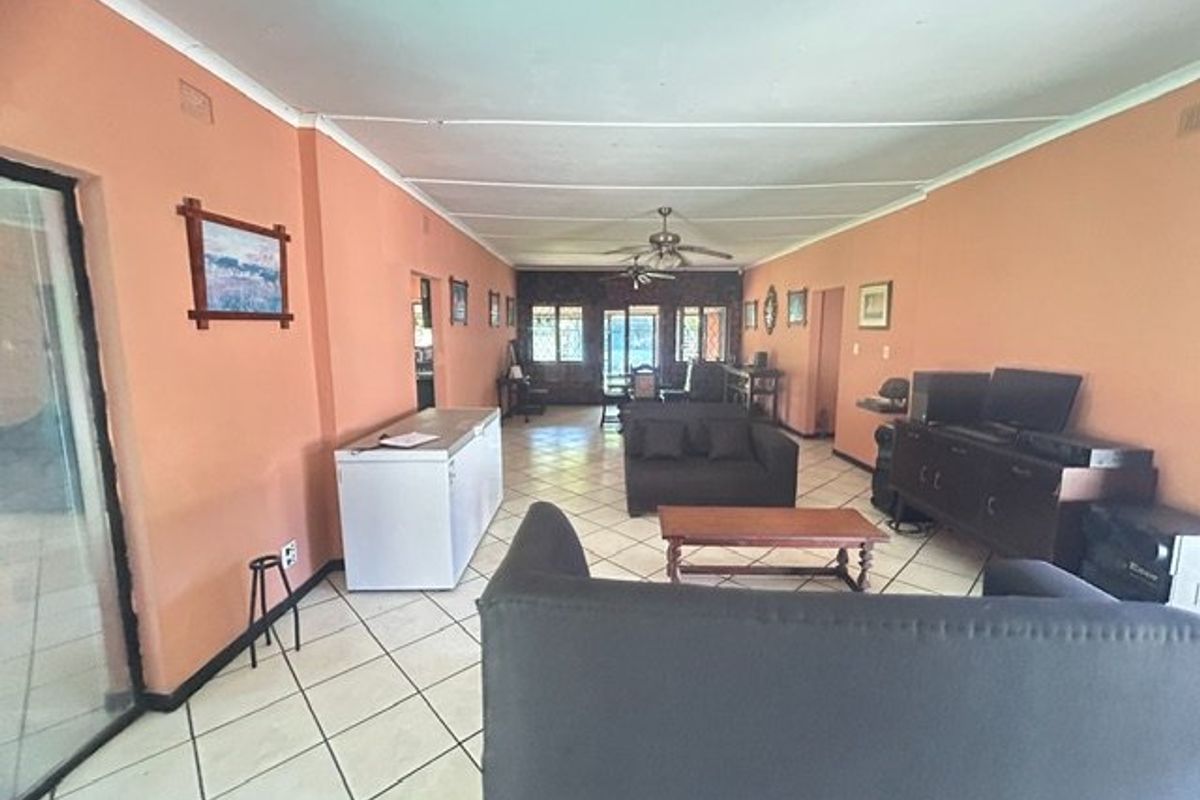 Spacious living area featuring tiled flooring and ceiling fans, offering a versatile layout with direct access to outdoor spaces.