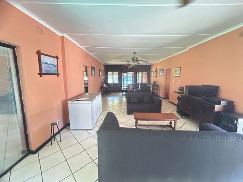 Spacious living area featuring tiled flooring and ceiling fans, offering a versatile layout with direct access to outdoor spaces.