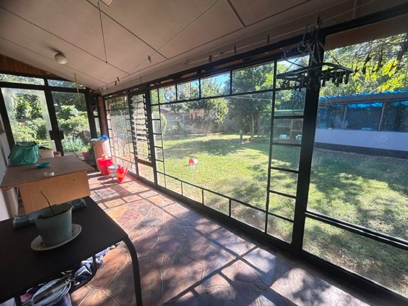 Enclosed patio area featuring flagstone flooring and extensive metal-framed glass windows overlooking the rear garden.