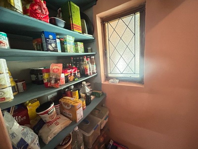A functional scullery or pantry area featuring built-in shelving and a leaded glass window, providing practical storage space.