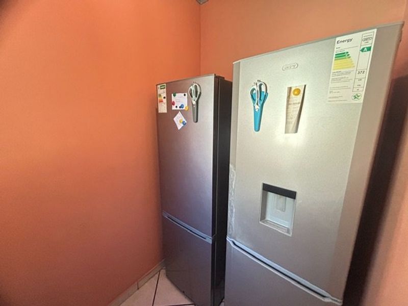 A corner view of a kitchen area featuring two large stainless steel refrigerators placed against a peach-colored wall.