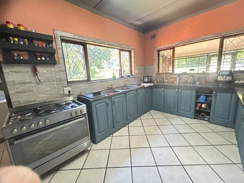 Spacious kitchen featuring a gas stove, double sink, ample built-in cabinetry, and large windows providing natural light.