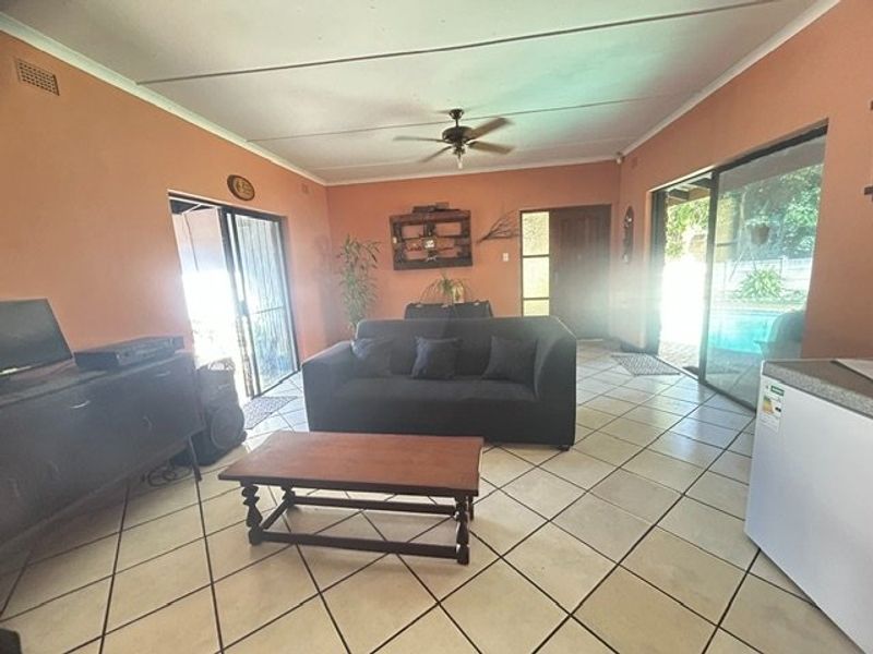 Spacious living room featuring tiled flooring, a ceiling fan, and large sliding glass doors providing natural light and access to the outdoor area.