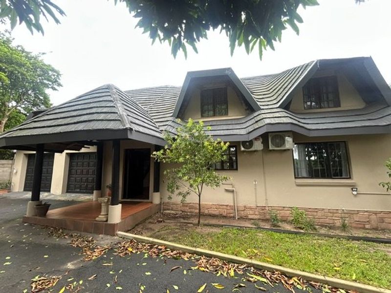 Front elevation of a multi-level house featuring a covered entrance, double garage, stone cladding accents, and a tiled roof.