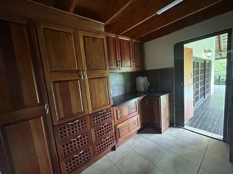 A kitchen featuring warm wooden cabinetry, stone countertops, and tiled flooring, with direct access to an outdoor deck area.