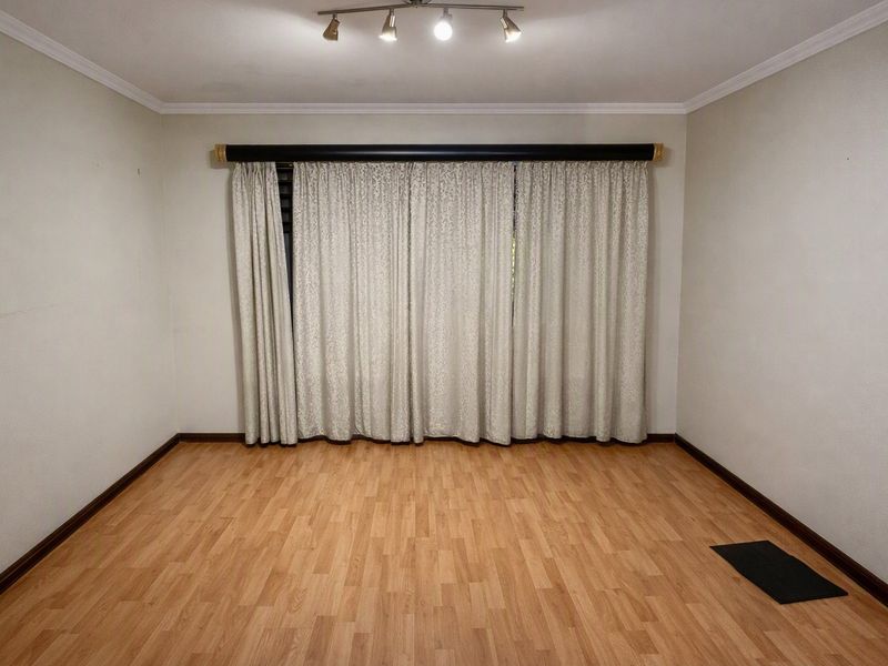 An empty living room featuring laminate flooring, coving, and track lighting, providing a blank canvas for personalization.