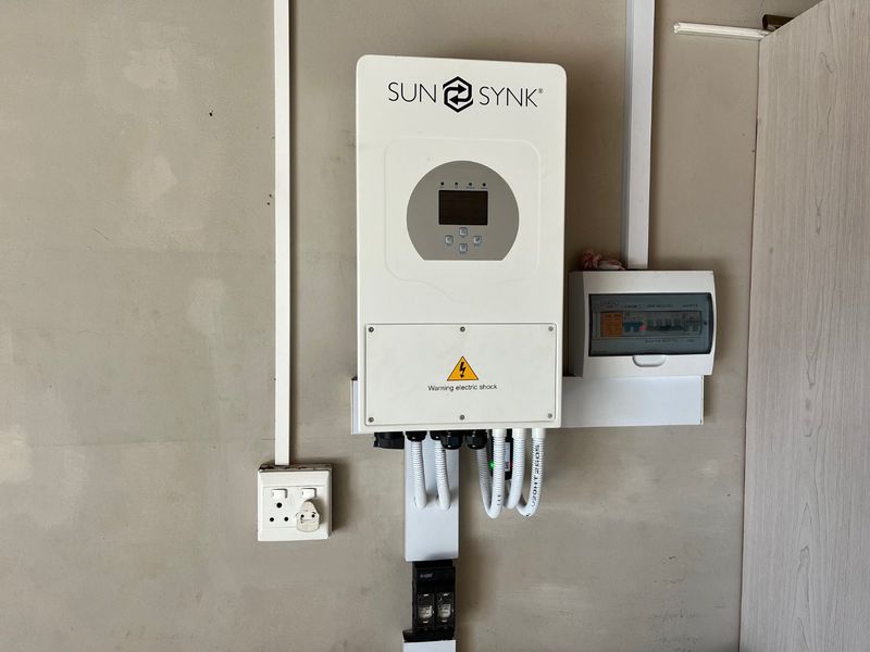 A wall-mounted Sunsynk solar inverter and electrical distribution board installation, providing modern energy management infrastructure.