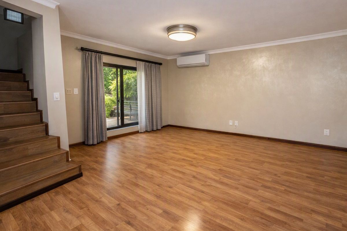 Spacious living area featuring laminate flooring, a built-in staircase, and a sliding glass door providing access to the outdoors.
