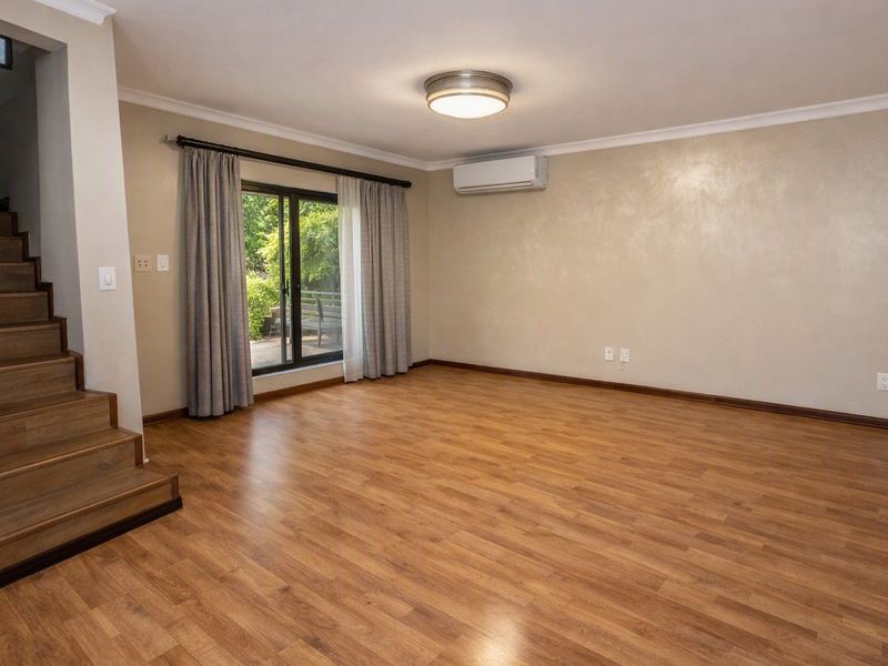 Spacious living area featuring laminate flooring, a built-in staircase, and a sliding glass door providing access to the outdoors.
