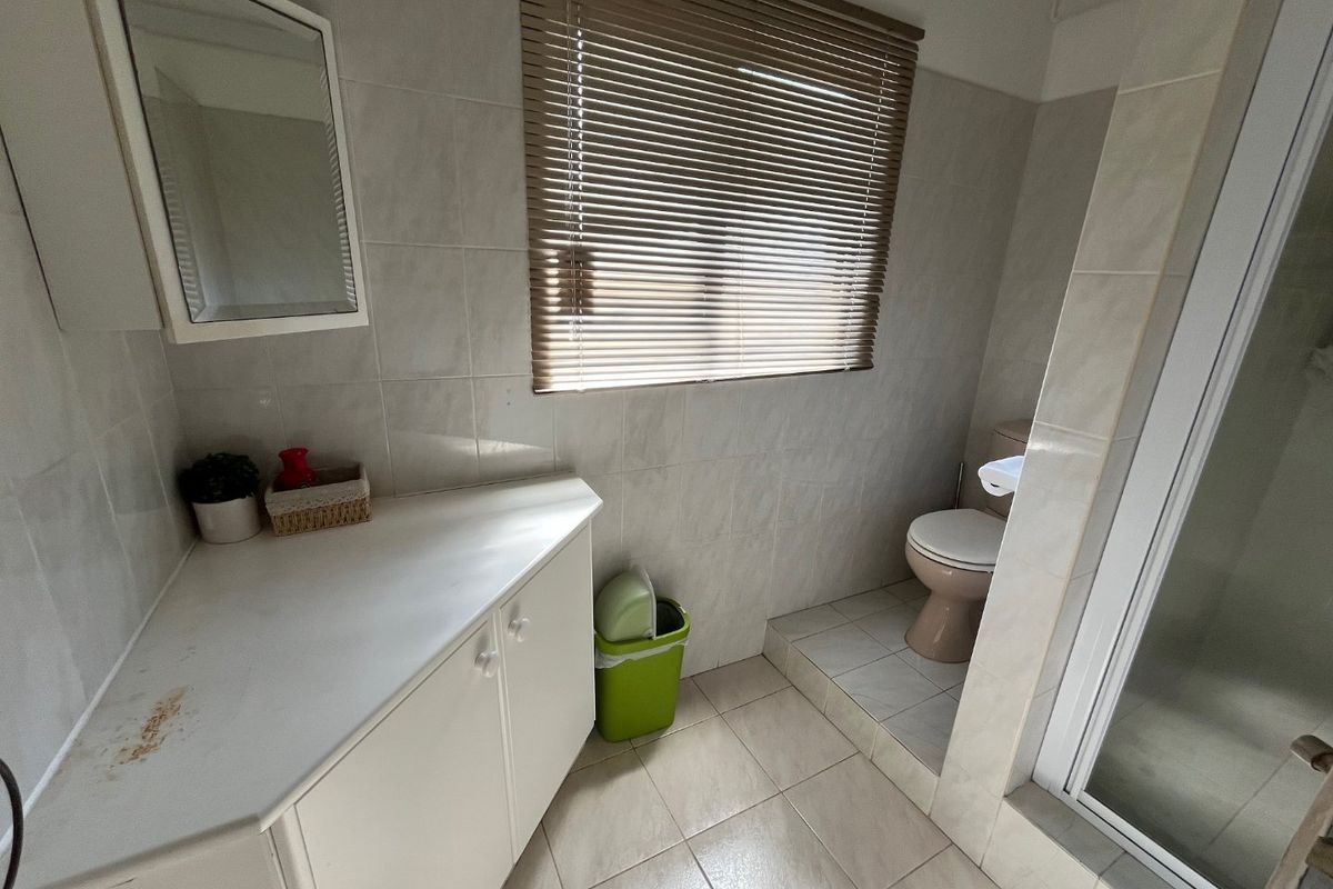 A functional bathroom featuring a built-in vanity, tiled walls and floors, a separate toilet area, and a shower enclosure.