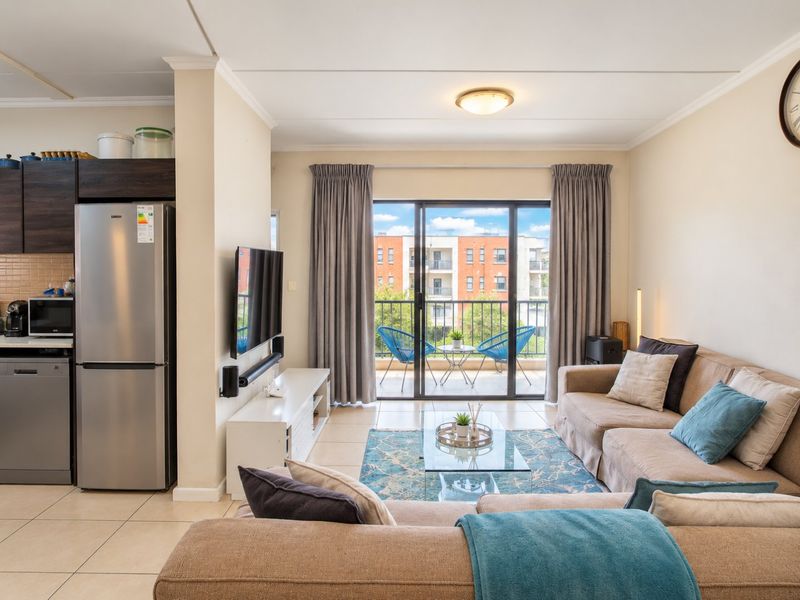 Open plan living area featuring tiled floors, integrated kitchen cabinetry, and sliding glass doors leading to a private balcony.