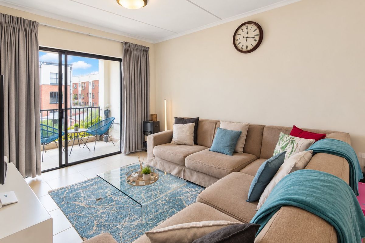 A bright living room featuring tiled flooring and a large sliding glass door that provides access to a private balcony.