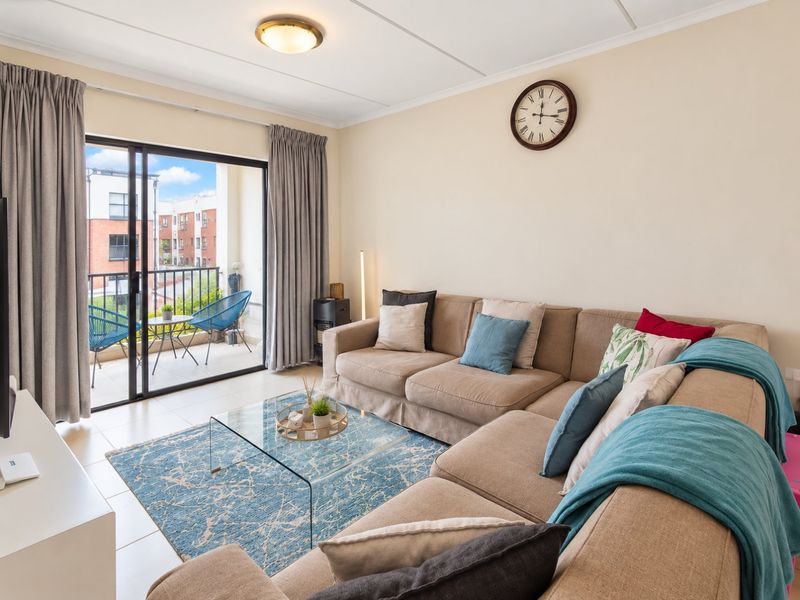 A bright living room featuring tiled flooring and a large sliding glass door that provides access to a private balcony.