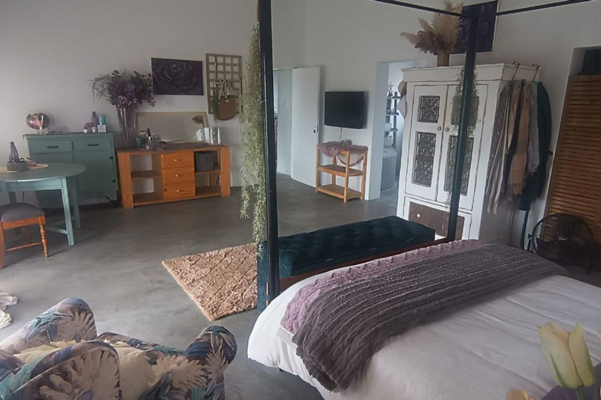 Spacious bedroom featuring polished concrete flooring and neutral wall finishes, offering a versatile layout with direct access to adjacent living areas.