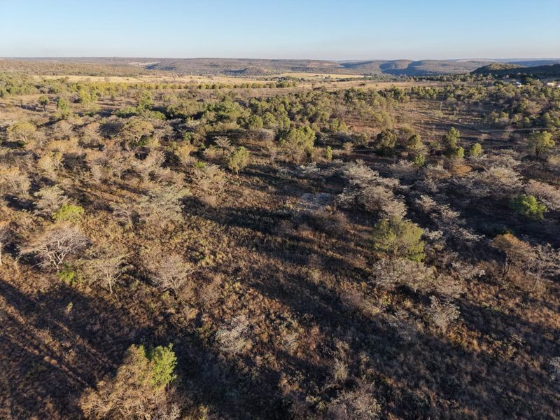 An aerial view of a vast, undeveloped landscape featuring native vegetation and rolling hills in the distance.