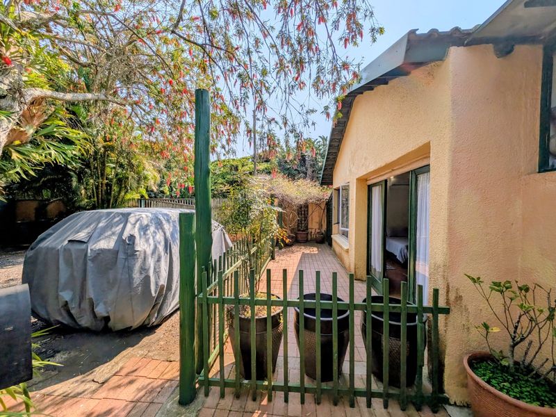A rear exterior view of the apartment featuring a paved patio area, timber fencing, and sliding glass door access to the interior.