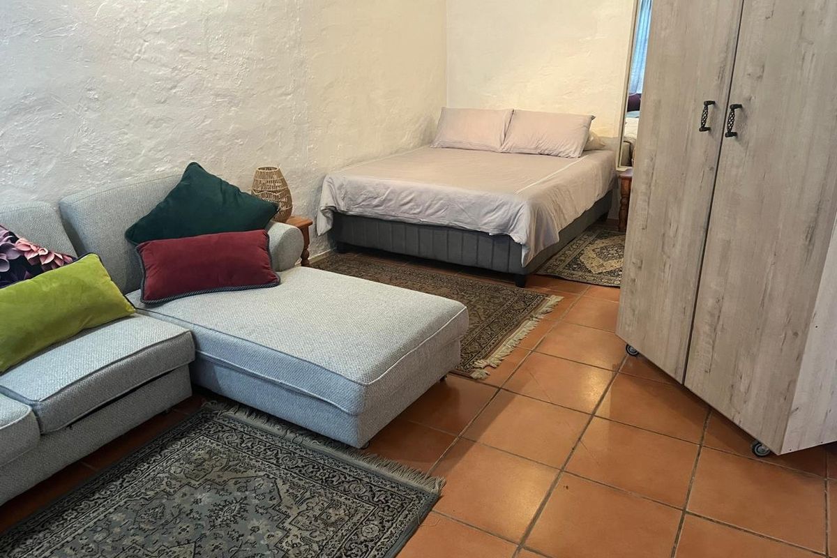 A bedroom featuring textured plaster walls and terracotta floor tiles, providing a functional living space.