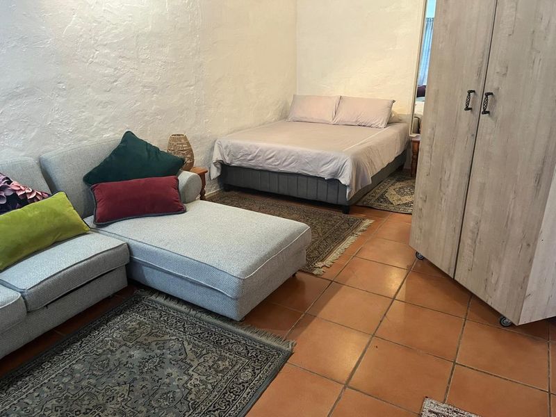 A bedroom featuring textured plaster walls and terracotta floor tiles, providing a functional living space.