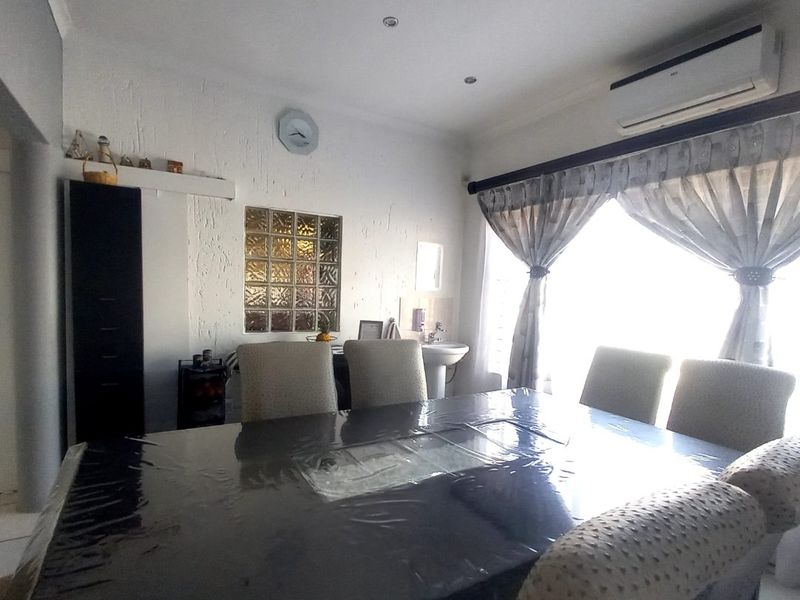 Dining room featuring a glass block feature wall, wall-mounted air conditioning unit, and a small pedestal basin.
