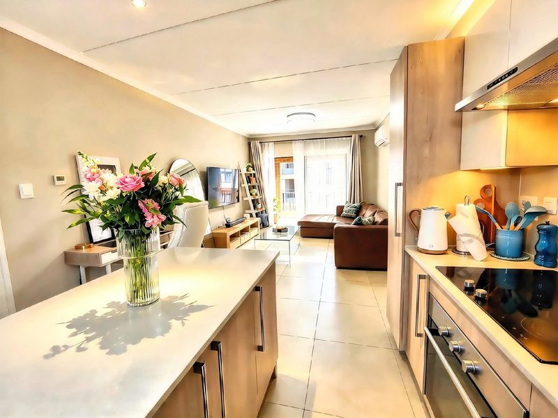 Modern open-plan living area featuring a well-equipped kitchen with island, sleek cabinetry, and seamless flow to a bright lounge with balcony access.
