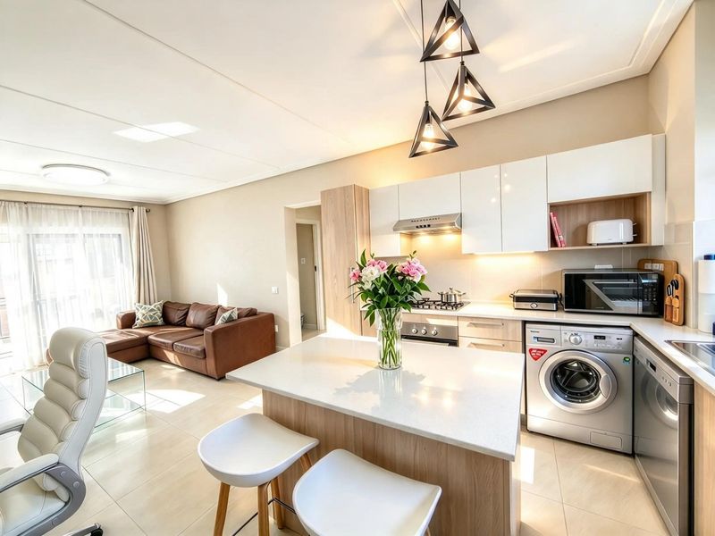 Modern open-plan living area featuring a sleek kitchen with quartz countertops, integrated appliances, and stylish pendant lighting, seamlessly flowing into the lounge space.