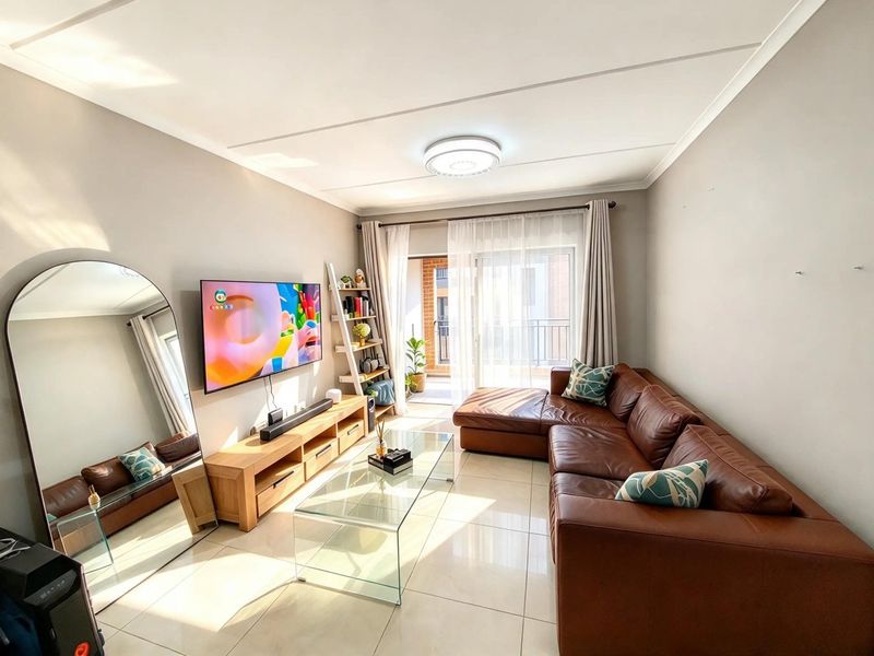Bright and modern living room featuring large format floor tiles, coved ceilings, and a sliding glass door providing access to an outdoor balcony area.