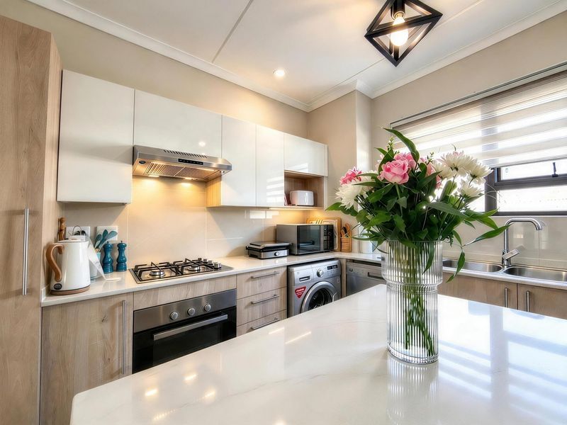 Modern kitchen featuring sleek cabinetry, stone countertops, a gas hob, built-in oven, and integrated appliances including a washing machine and dishwasher.