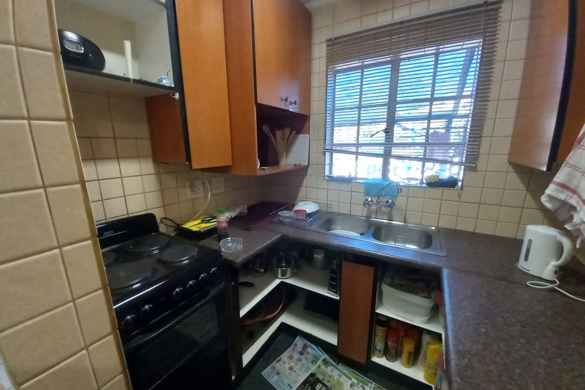 Compact kitchen featuring laminate cabinetry, a double bowl stainless steel sink, and an electric stove with tiled splashback finishes.