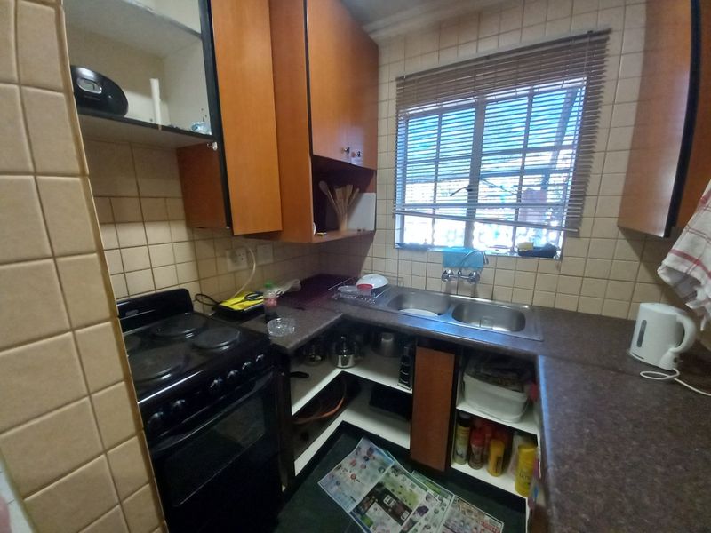 Compact kitchen featuring laminate cabinetry, a double bowl stainless steel sink, and an electric stove with tiled splashback finishes.