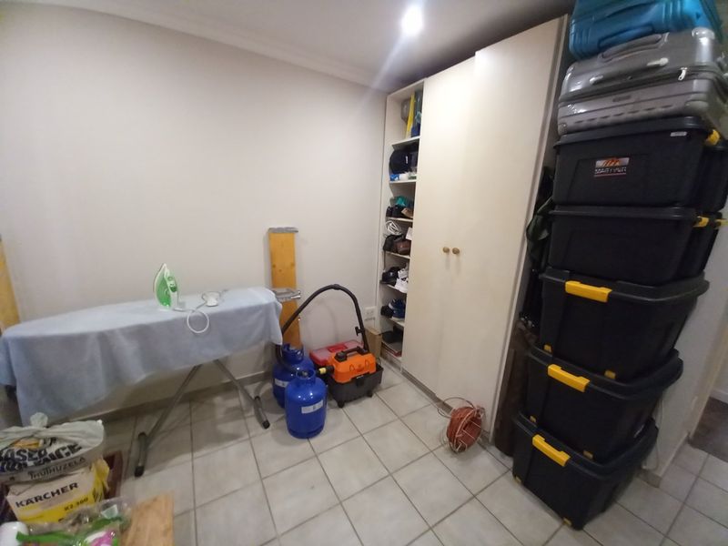 A functional utility space featuring tiled flooring and a built-in storage cupboard, suitable for laundry or general household storage needs.