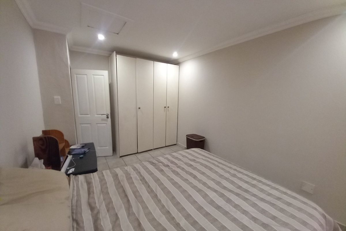 A well-maintained bedroom featuring neutral walls, recessed downlighting, and ample built-in cupboard storage space.