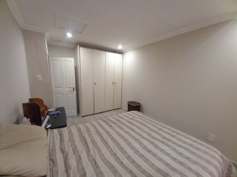 A well-maintained bedroom featuring neutral walls, recessed downlighting, and ample built-in cupboard storage space.