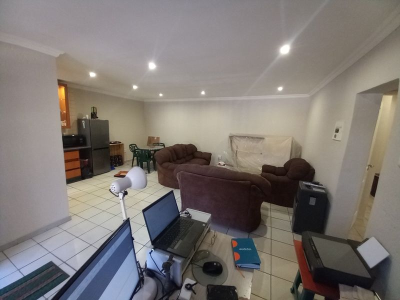 Open plan living and kitchen area featuring tiled flooring and recessed downlighting, offering a functional layout for modern apartment living.