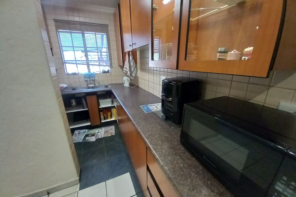 A functional kitchen featuring laminate cabinetry, dark countertops, a double basin sink, and a tiled backsplash, offering a practical layout for daily use.