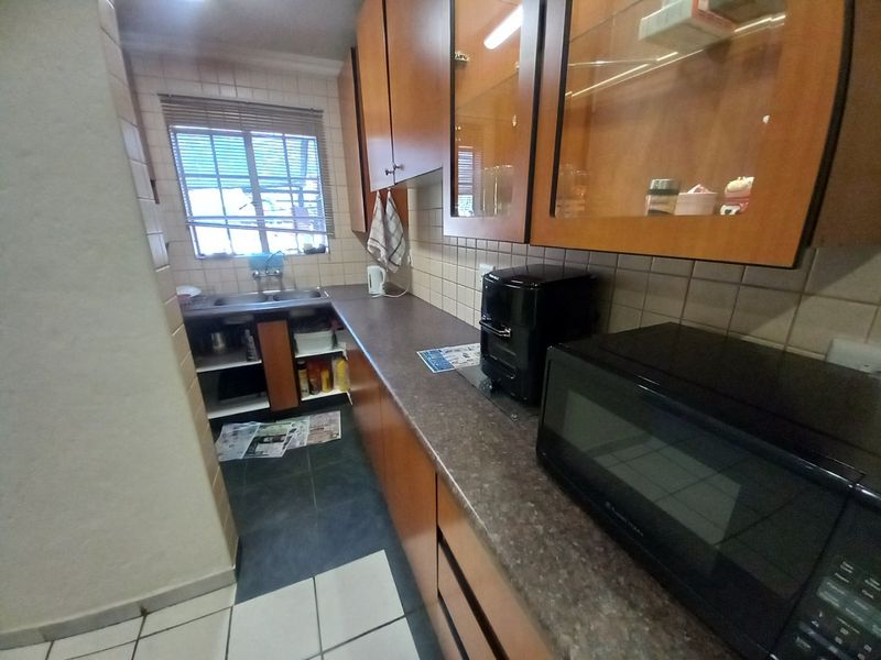 A functional kitchen featuring laminate cabinetry, dark countertops, a double basin sink, and a tiled backsplash, offering a practical layout for daily use.