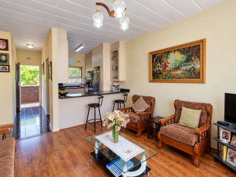 Open-plan living area featuring laminate flooring, a functional kitchen with granite countertops, a breakfast bar, and direct access to an outdoor balcony.