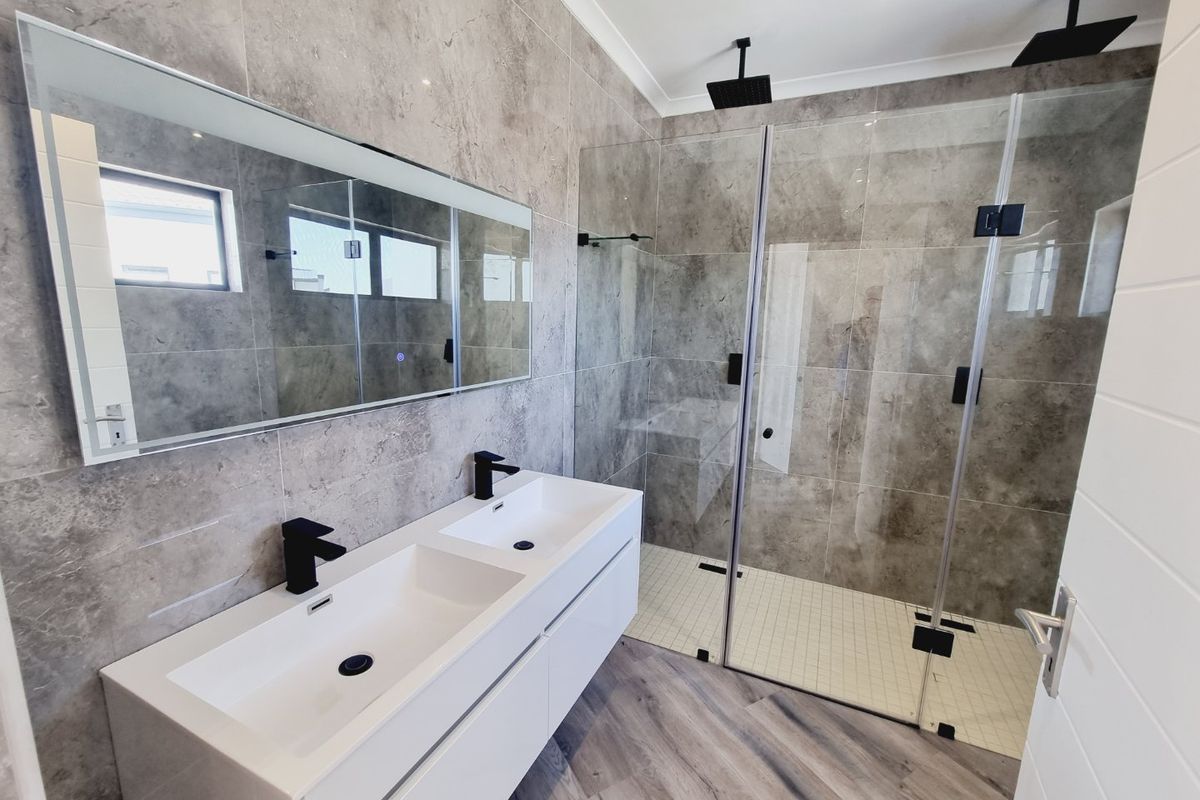 Modern bathroom featuring a double vanity with matte black fixtures, a spacious walk-in shower with dual shower heads, and contemporary grey tiling.
