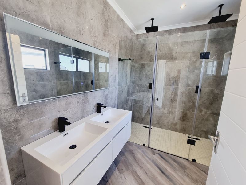 Modern bathroom featuring a double vanity with matte black fixtures, a spacious walk-in shower with dual shower heads, and contemporary grey tiling.