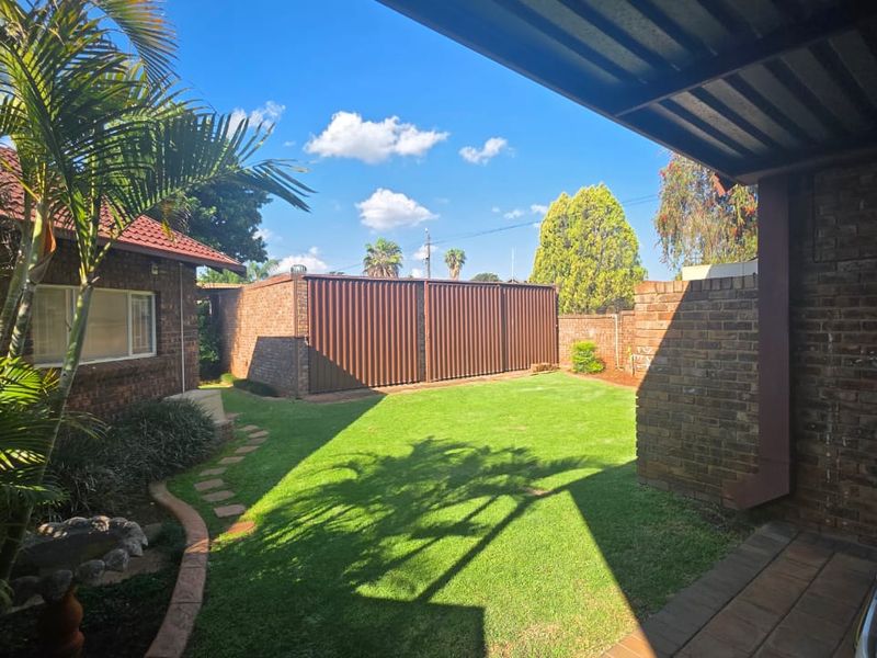 A well-maintained rear garden featuring a lush lawn, brick boundary walls, and a covered patio area, providing a private outdoor space.
