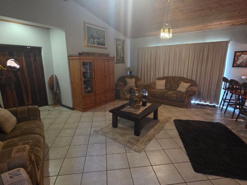 Spacious living room featuring vaulted timber ceilings, tiled flooring, and a built-in bar area, offering a warm and traditional aesthetic.