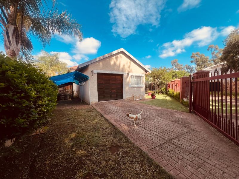 Front view of the property featuring a paved driveway, single garage, and secure metal perimeter fencing.