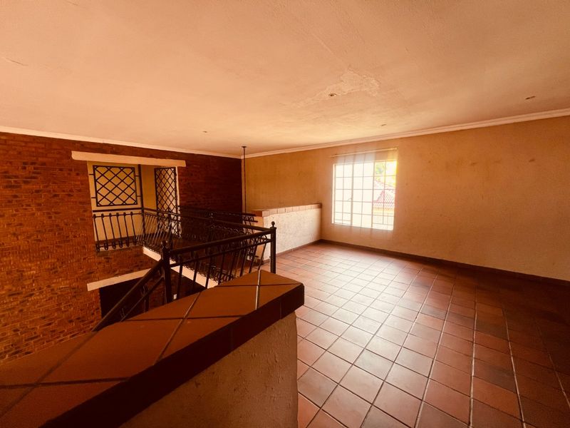 Spacious landing area featuring terracotta tiling, exposed brickwork, and a wrought iron balustrade overlooking the lower level.